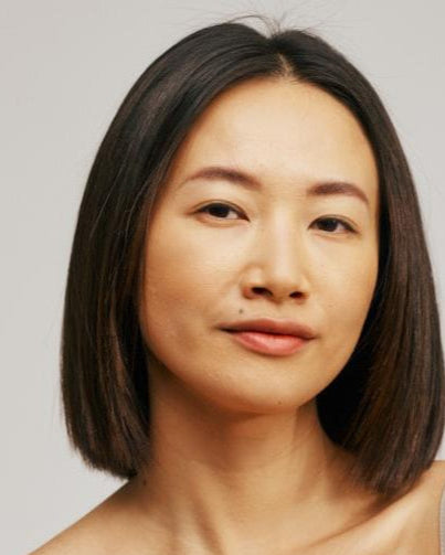 Woman wearing a beige tank top against a plain background